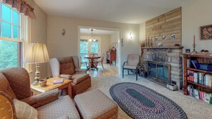 Ein gemütliches Wohnzimmer mit Kamin, Bücherregal und Essbereich mit Tisch und Stühlen.