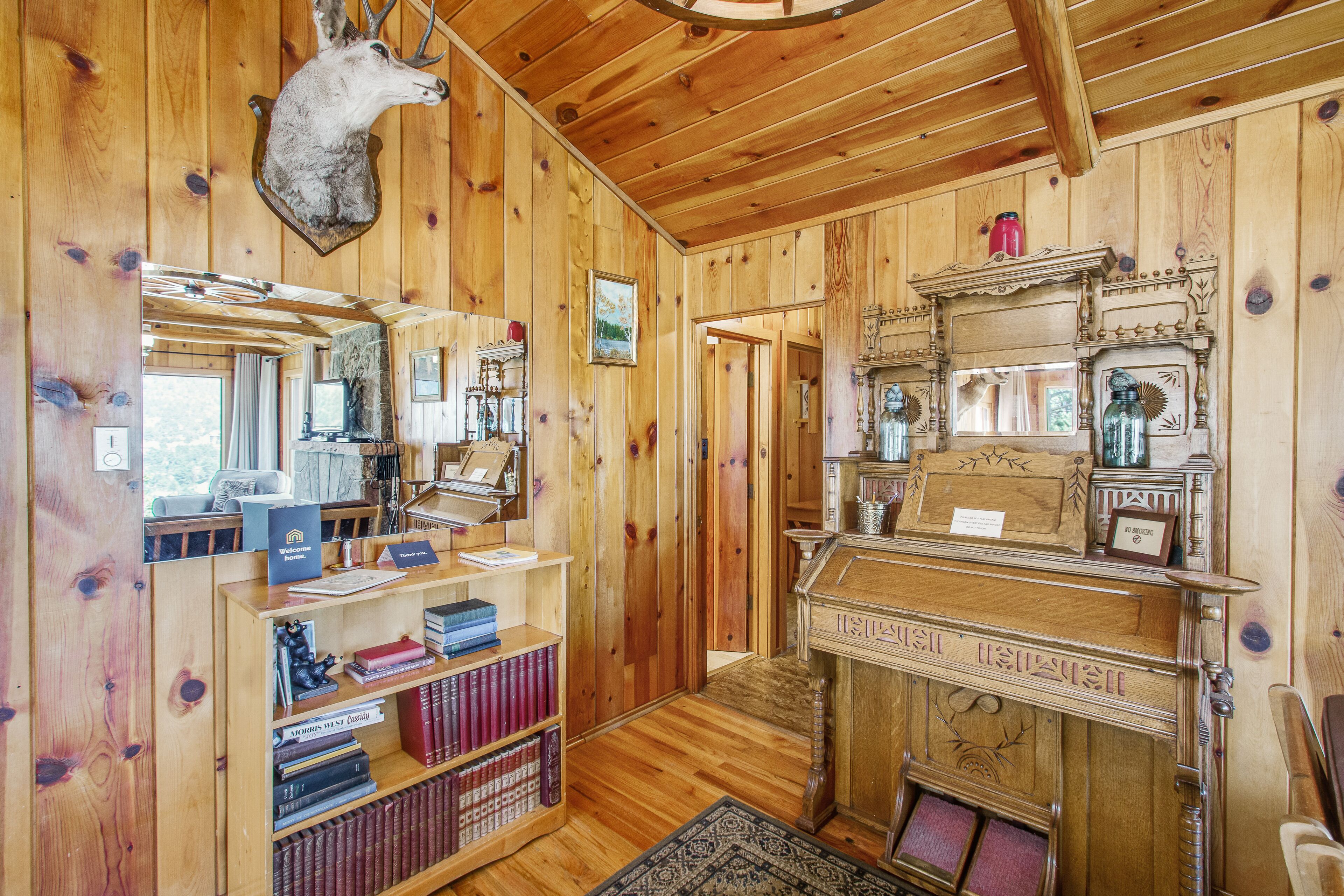 A wooden interior with a fireplace, bookshelves, and a mounted animal head.