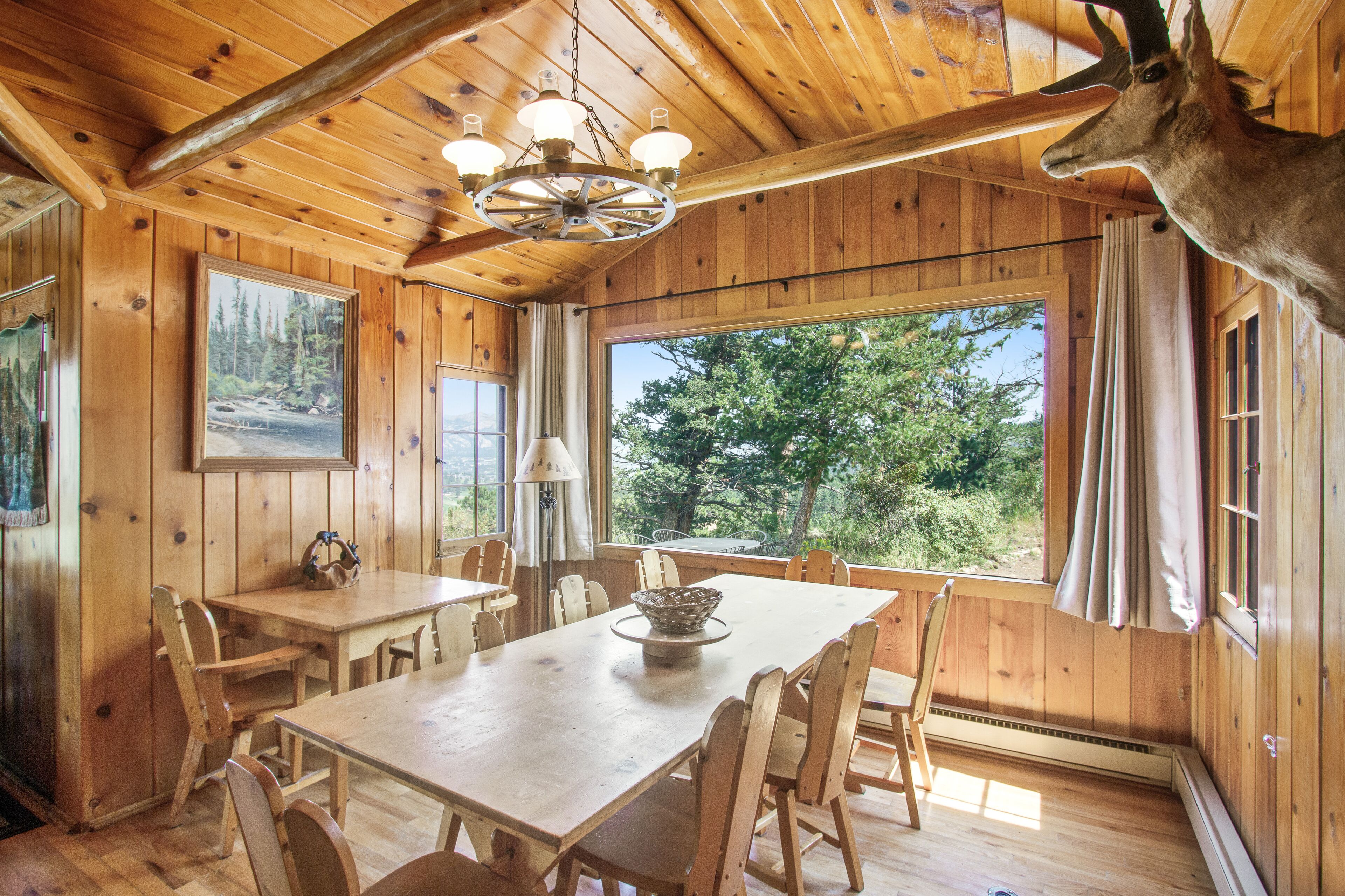 A wooden dining area with a table, chairs, and a chandelier.
