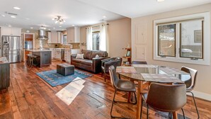 En rummelig opholdsstue med stor sofa, spisebord og et køkken i baggrunden.