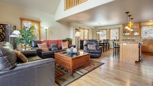 A spacious living room with a leather sofa, a coffee table, and a dining area with chairs and a table. - 3BR Three-story home with epic mountain views & fireplace (Estes Park)