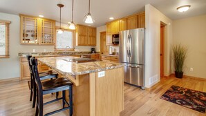A modern kitchen with wooden cabinets, stainless steel appliances, and a granite countertop. - 3BR Three-story home with epic mountain views & fireplace (Estes Park)