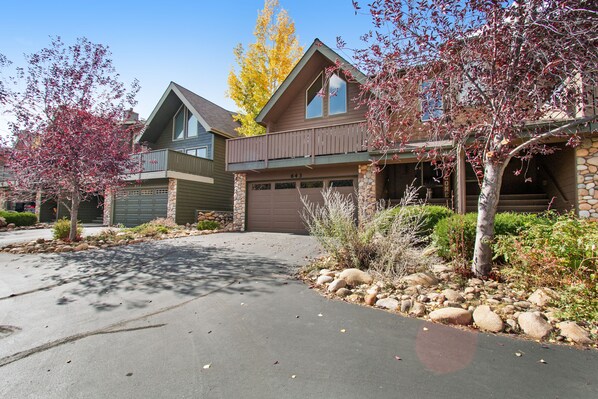 A two-story house with a stone facade, a garage, and a driveway. - 3BR Three-story home with epic mountain views & fireplace (Estes Park)