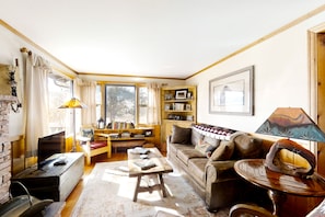A cozy living room with a fireplace, a wooden coffee table, a sofa, and a bookshelf. - Delightful Getaway with Free WiFi, a Wood Fireplace, Washer/Dryer, & Great Views (Estes Park)