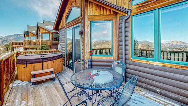 A wooden cabin with a deck, a hot tub, and a table with chairs. - Two BR condo w/ Brand NEW HOT TUB and great views! Community pool perfect for kids (Estes Park)