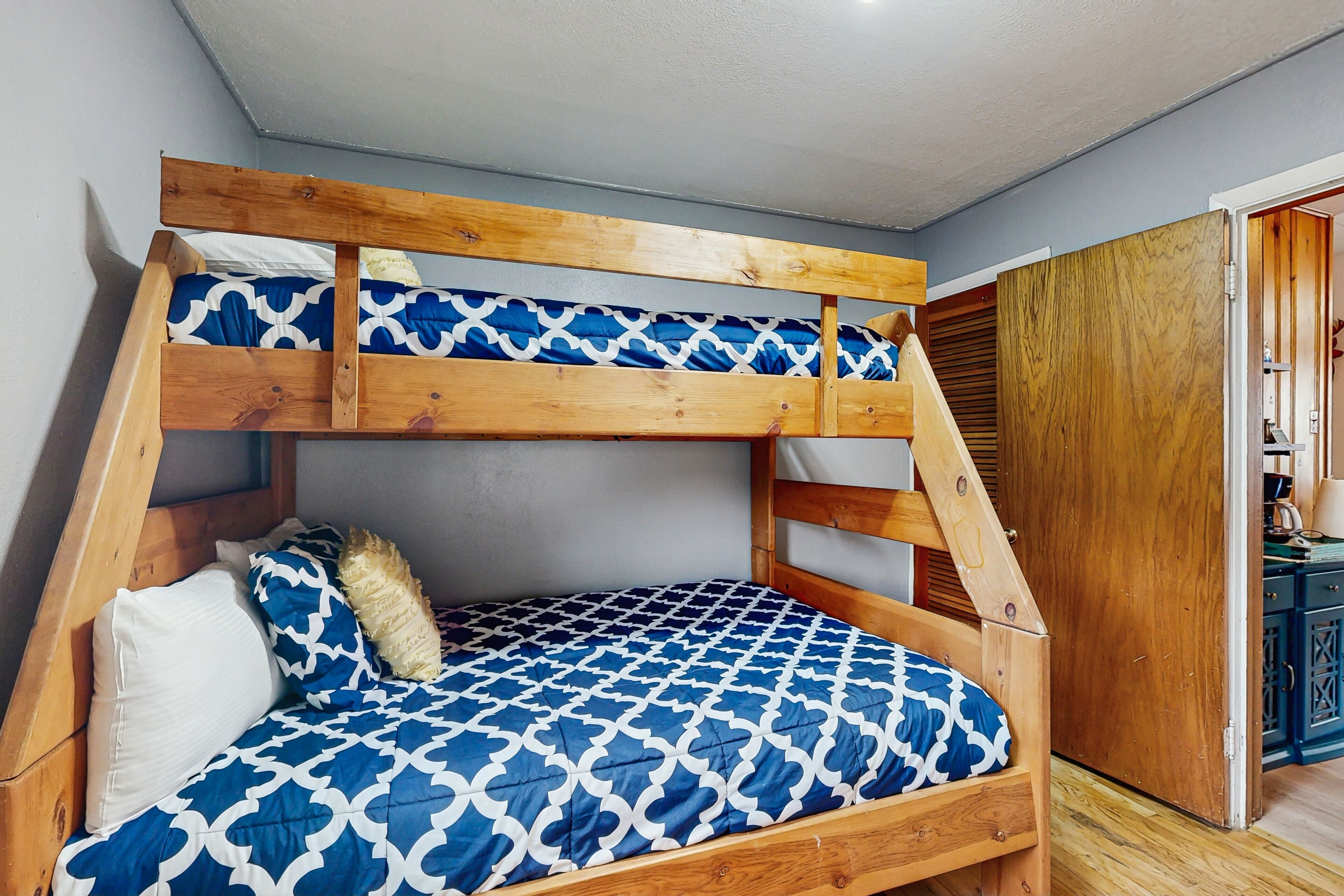 Un lit superposé avec une couvre-lit à motifs bleus et une tête de lit en bois.