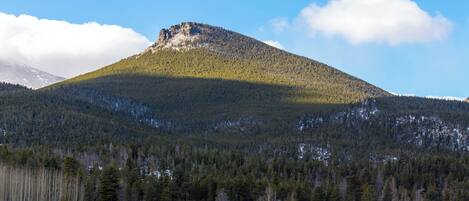 Ein Berg mit bewaldeter Flanke und blauem Himmel.