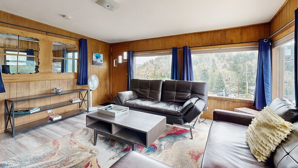 En moderne stue med en lædersofa, et sofabord og et bogreol.