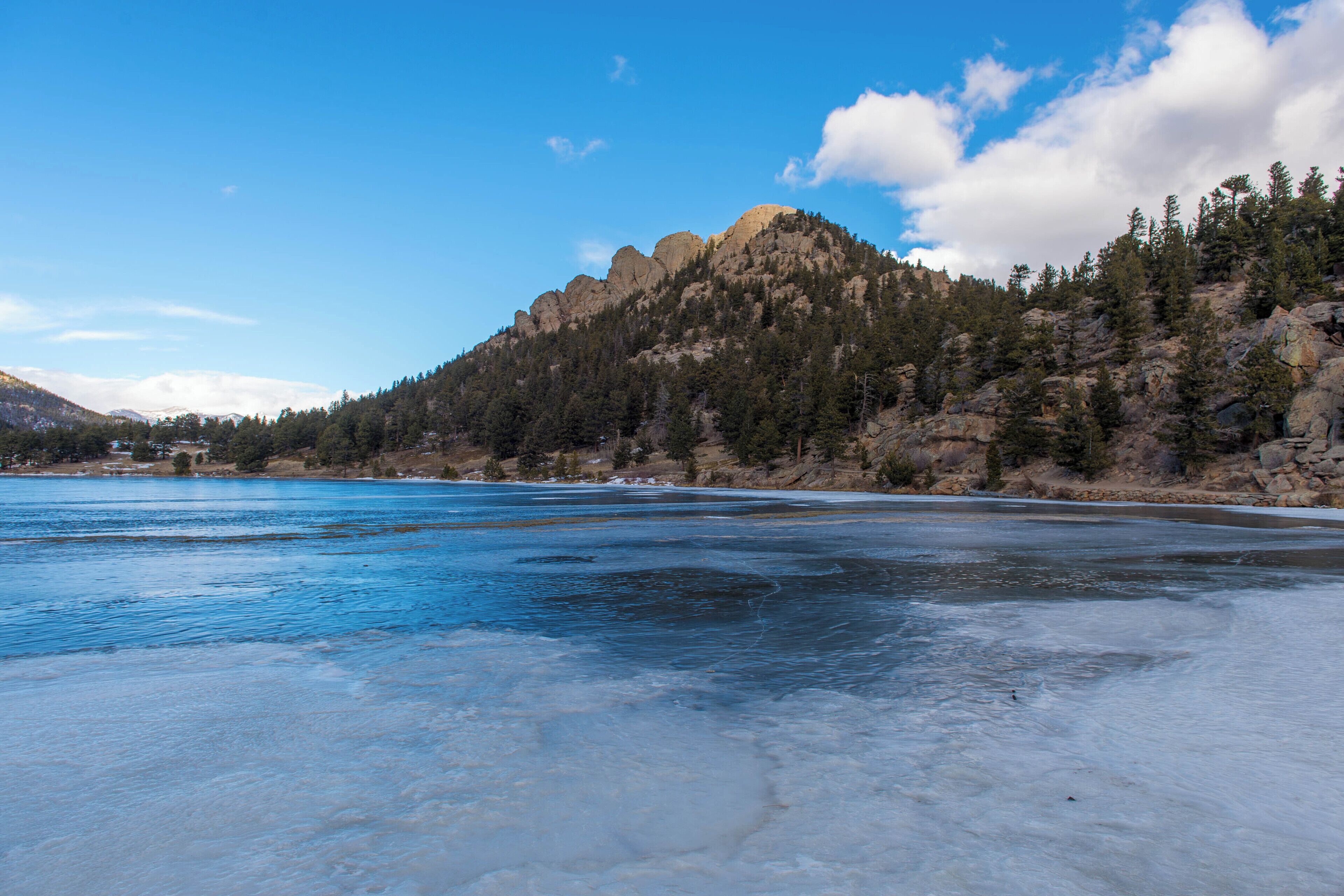 A frozen lake with a mountainous backdrop and a clear sky.