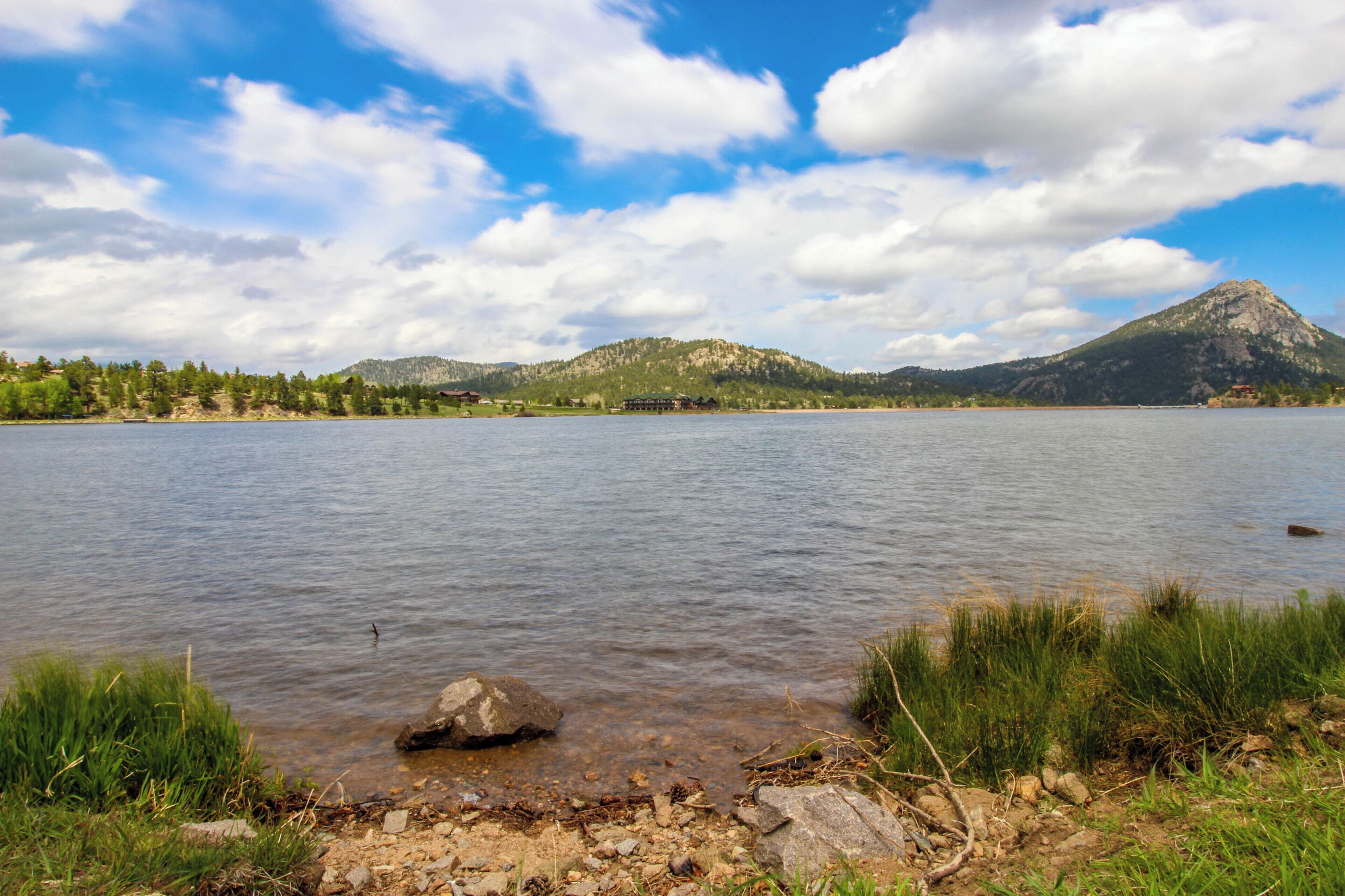 A lake with a mountain in the background, a clear sky, and a rocky shoreline.