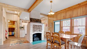 A cozy room with a fireplace, wooden furniture, and a dining area. - Charming cabin with full kitchen, furnished deck, & incredible views (Estes Park)