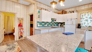 A kitchen with wooden walls, a granite countertop, and a refrigerator. - Charming cabin with full kitchen, furnished deck, & incredible views (Estes Park)