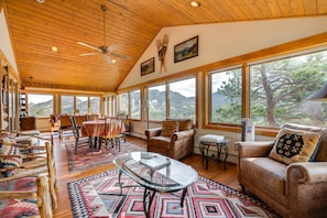 A spacious living room with a high ceiling, wooden beams, large windows, and a mountain view. - Historic cabin with mountain views, private W/D, & furnished deck (Estes Park)