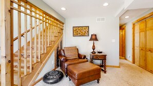 A staircase with wooden railings, a leather armchair, a matching ottoman, a small table with a lamp, and a decorative wall piece. - Wonderful family cabin w/stunning views, free WiFi, & full kitchen - near trails (Estes Park)