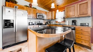 A modern kitchen with wooden cabinets, stainless steel appliances, and a central island with seating. - Wonderful family cabin w/stunning views, free WiFi, & full kitchen - near trails (Estes Park)