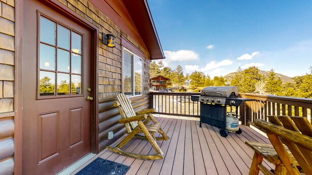 A wooden deck with a grill, rocking chairs, and a door. - Wonderful family cabin w/stunning views, free WiFi, & full kitchen - near trails (Estes Park)