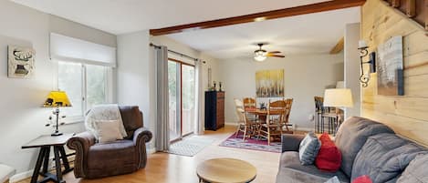 A spacious living room with a fireplace, a dining area, and a staircase leading to another level.