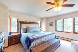 Ein Schlafzimmer mit einem großen Bett, einer Holzbank, einem Nachttisch und einem Deckenventilator.