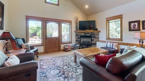 A spacious living room with a fireplace, leather sofas, a coffee table, and large windows. - Modern home with full kitchen, patio, great location-Dogs Welcome (Estes Park)