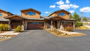 A modern two-story house with a stone facade, large garage doors, and a well-maintained driveway. - Modern home with full kitchen, patio, great location-Dogs Welcome (Estes Park)