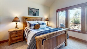 A bedroom with a wooden bed, two nightstands, a window with a view of the outdoors, and a ceiling fan. - Modern home with full kitchen, patio, great location-Dogs Welcome (Estes Park)