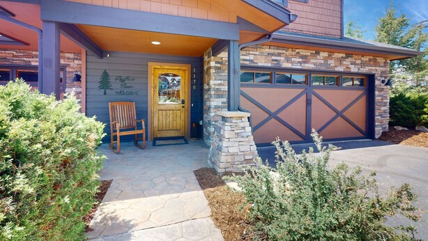 A modern two-story house with a stone facade, a wooden front door, and a garage with a brown garage door. - Modern home with full kitchen, patio, great location-Dogs Welcome (Estes Park)