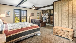 Un dormitorio con una cama grande, un aparador de madera, una silla y una pared de piedra.