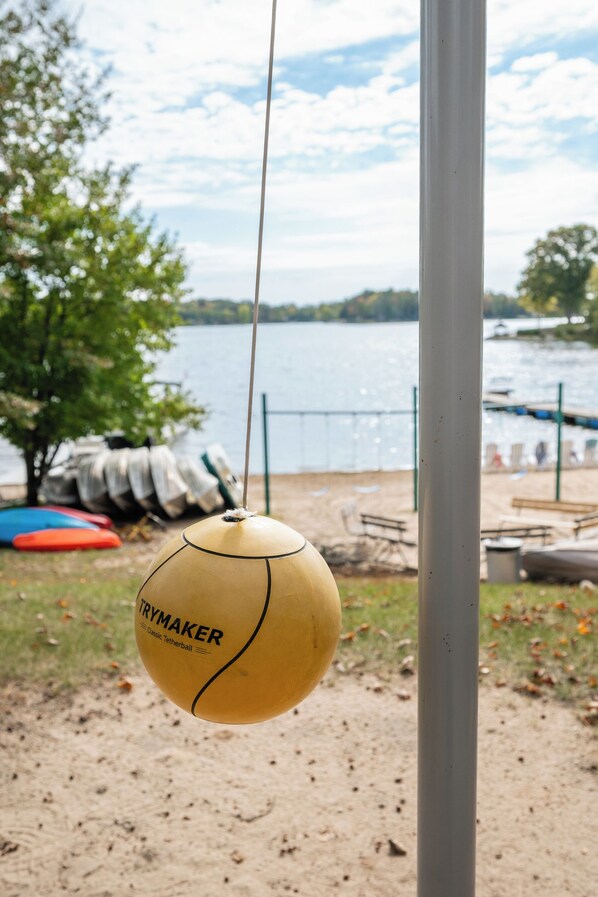 A yellow Trymacker Classic Tetherball hanging from a pole by a lake. - Hilltop Haven at Sommer Dorf (West Branch)