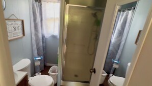 Ein kleines Badezimmer mit zwei Toiletten, einer Dusche und einer Glaswand.