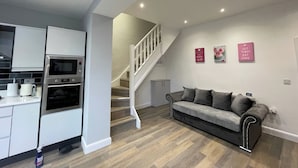 Une cuisine moderne dotée d’appareils électroménagers intégrés, un canapé gris et un escalier menant à un autre niveau.
