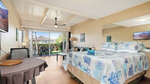 A bedroom with a large bed, a dining table, and a sliding glass door leading to a patio. - KBS A107 - Updated Studio next to Beach (Kihei)