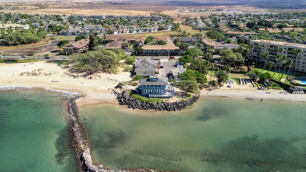 An aerial view of a coastal residential area with houses, a beach, and a rocky shoreline. - KBS A107 - Updated Studio next to Beach (Kihei)
