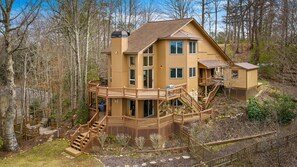A multi-story wooden cabin with a deck and stairs, surrounded by trees. - Peaks & Quiet Retreat - Views From Every Room and Dog Friendly (Morganton)