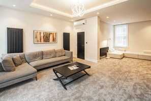 Una sala de estar moderna con un sofá gris, una mesa de centro negra y un sofá blanco.
