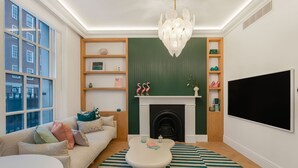 Una sala de estar con sofá, mesa de centro, chimenea, televisor y candelabro.