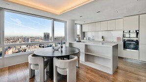 Une cuisine moderne avec des meubles blancs et une grande fenêtre donnant sur un paysage urbain.