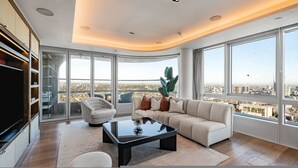 Un salon moderne avec une grande fenêtre, un canapé, une table basse et un téléviseur.