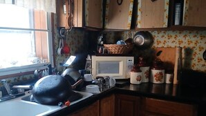 Una cocina con gabinetes de madera, un microondas y varios utensilios.