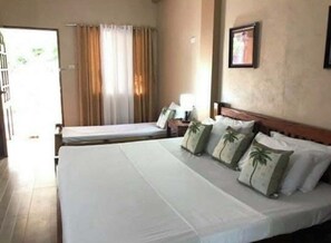 Una habitación de hotel con una cama grande, una cama más pequeña, una mesita de noche, una lámpara y una ventana con cortinas.
