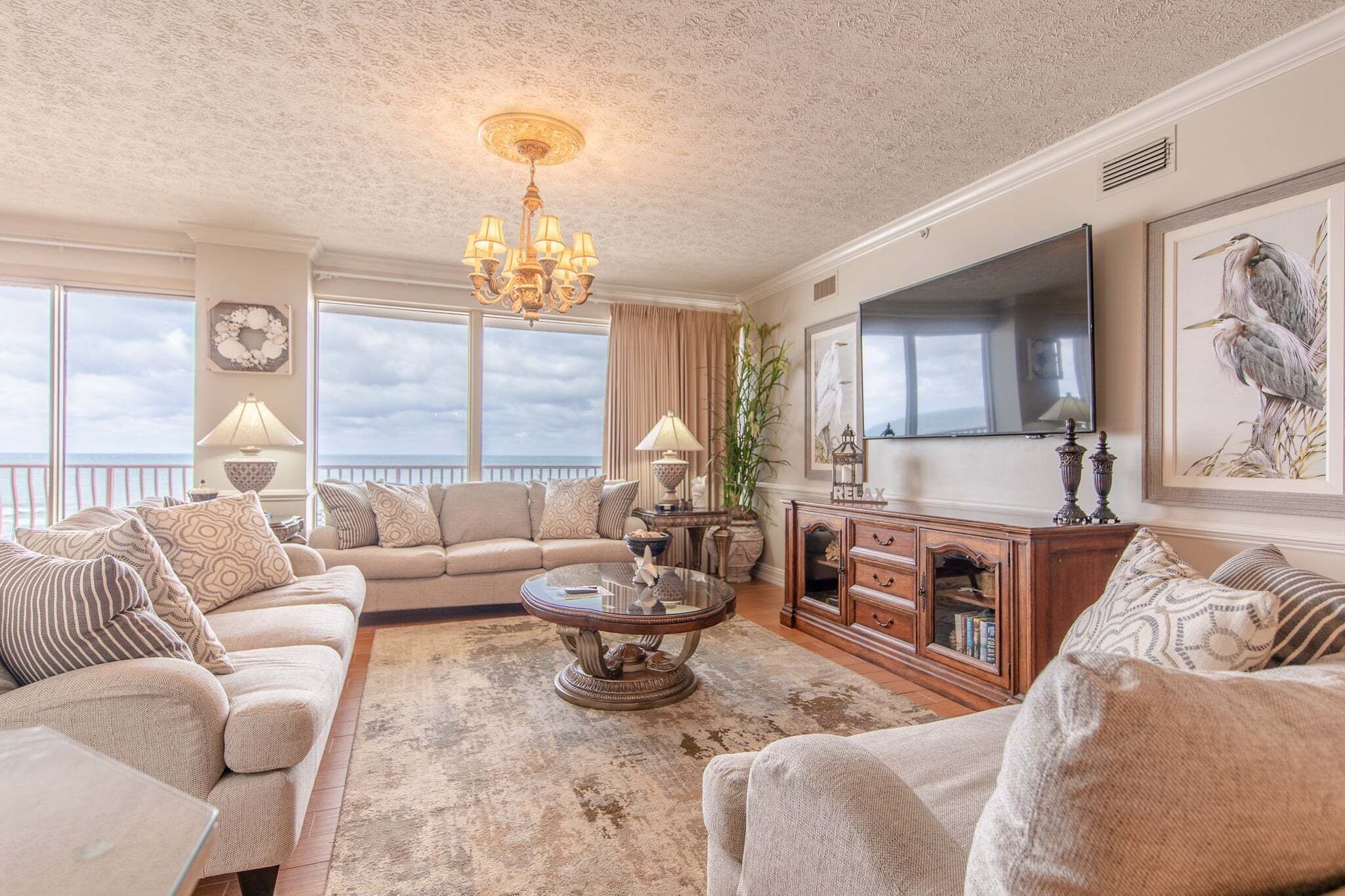 A spacious living room with a sofa set, a coffee table, a TV, and a large window with a view.