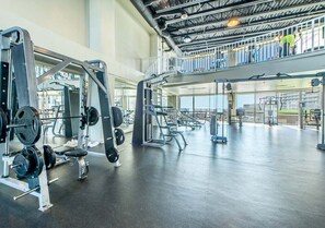 A spacious gym with various weightlifting equipment, a mezzanine level, and large windows. - Deja Blue 1831–Pools & Beach–Sleeps 8 (Panama City)