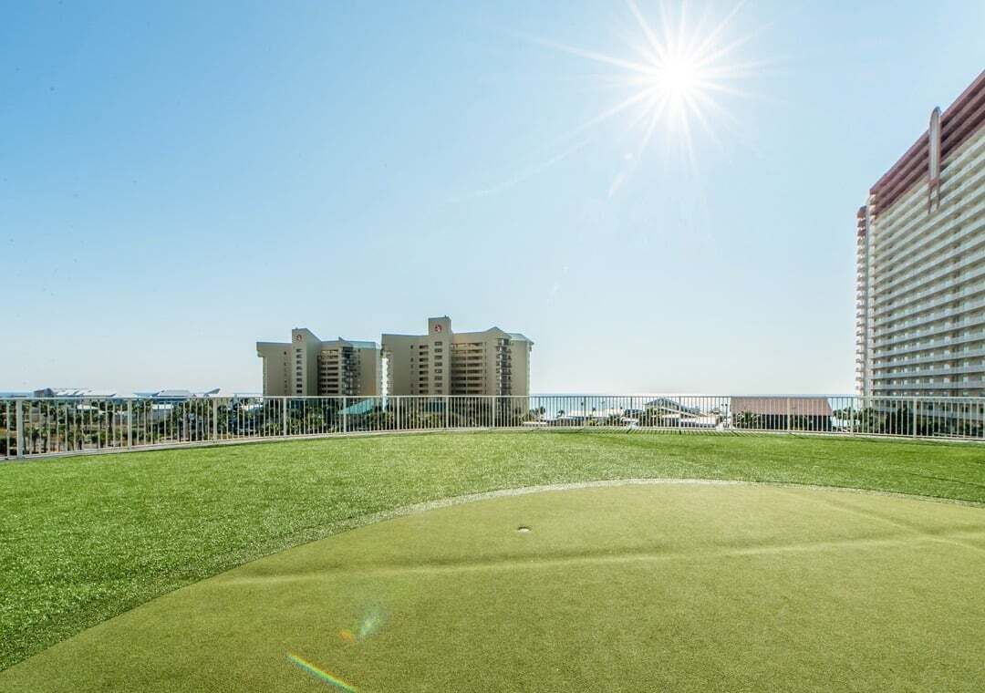 Un terrain de golf avec un ciel dégagé et des bâtiments en arrière-plan.