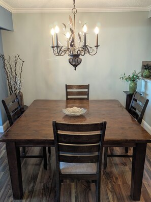A dining room with a wooden table, six chairs, a chandelier, and decorative vases. - Spacious home with view. Quick Highway access. Ample Parking. 3 month rentals. (Coquitlam)