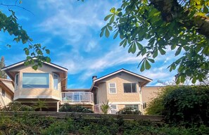 Ein zweistöckiges Haus mit Balkon, Garage und Holzzaun.