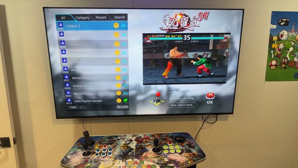A gaming setup with a TV displaying a fighting game, a joystick, and a gamepad. - Luxurious, peaceful, & fun 4-bedroom house with a game room in charming La Porte (La Porte)