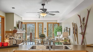 A modern kitchen with a central island, double sinks, and a ceiling fan. - Rustic Creekside Retreat 2BR and 2BT with Stunning View! (Canmore)