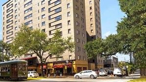 Un immeuble à plusieurs étages, doté d’une façade sobre, de nombreuses fenêtres et d’un tramway devant.
