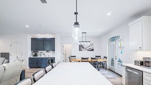 Eine moderne Küche mit Kochinsel, eingebauten Schränken und einem Essbereich mit langem Tisch und Stühlen.