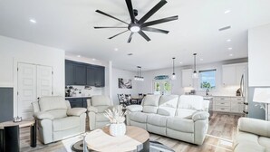 Ein modernes Wohnzimmer mit einem großen Deckenventilator, einem runden Couchtisch und einer Sofagarnitur.