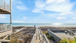 Eine Holzterrasse führt zu einem Strand mit freiem Blick auf den Ozean.